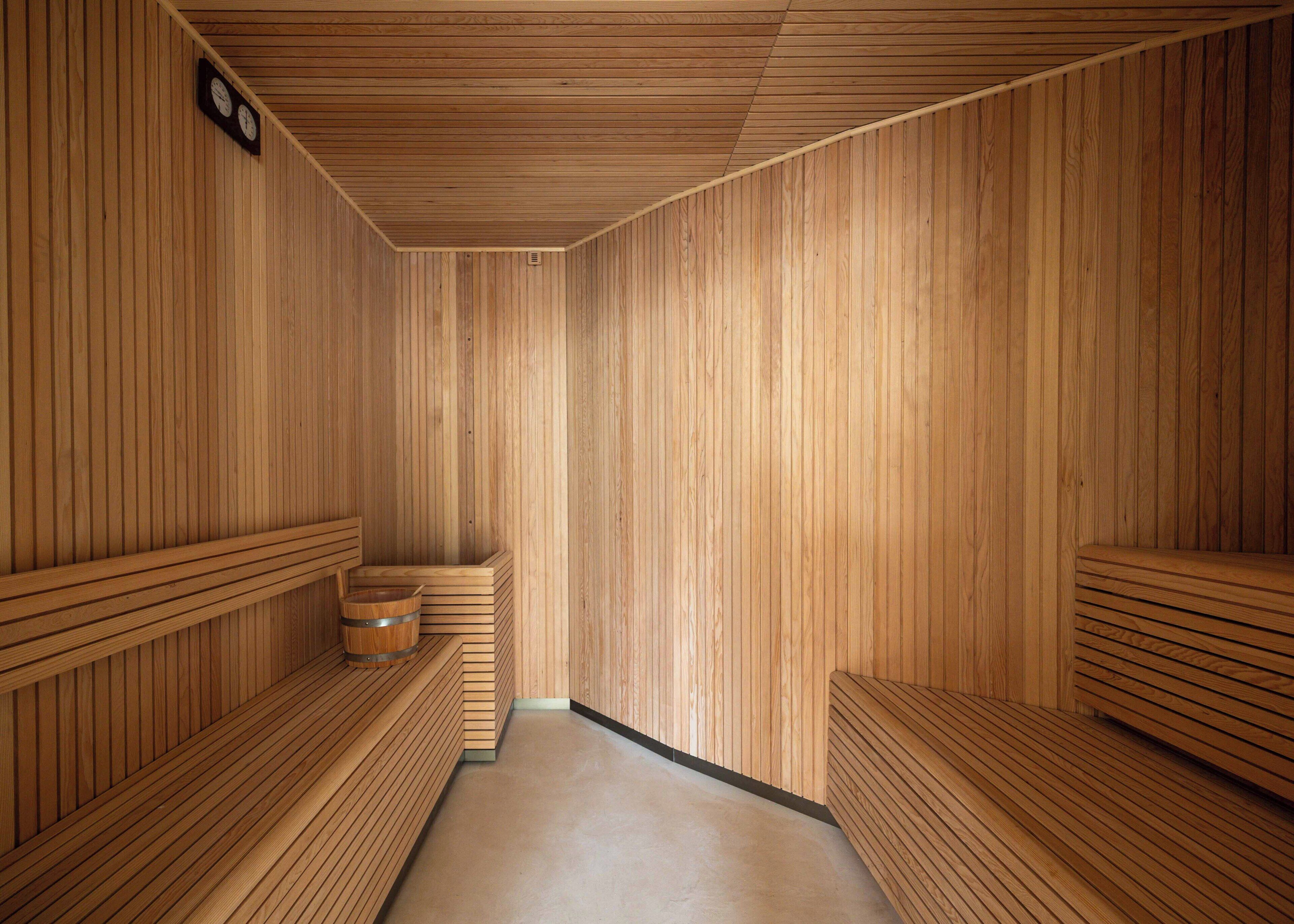 Una sala de sauna con bancos de madera, suelo de madera y un reloj en la pared.