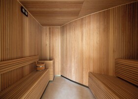 A sauna room with wooden benches and benches, a wooden floor, and a clock on the wall.