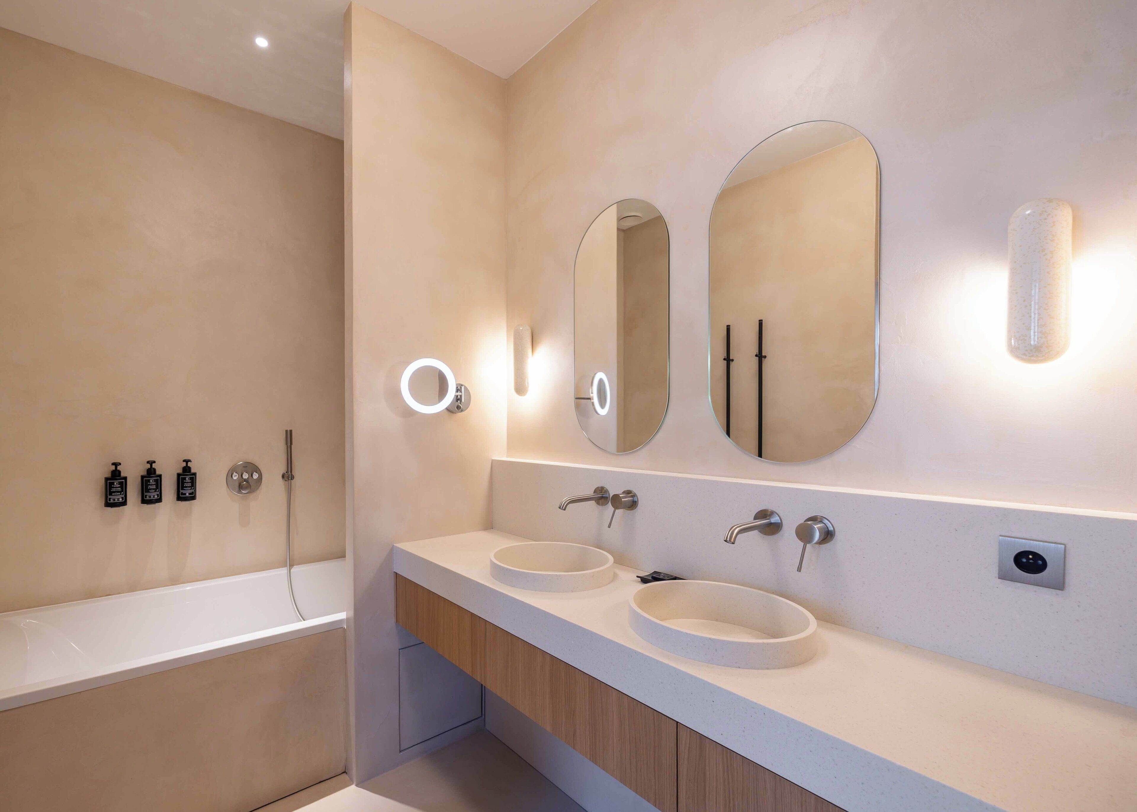 Un baño moderno con bañera, dos lavamanos y tres espejos.