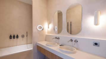 Un baño moderno con bañera, dos lavamanos y tres espejos.