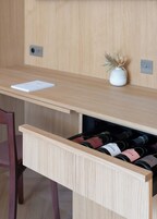 A wooden desk with a drawer containing wine bottles.