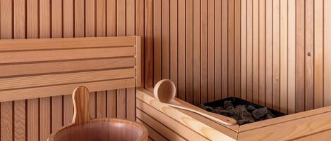 Una sauna de madera con una bañera de madera, un banco de madera y un recipiente de madera con una banda metálica.