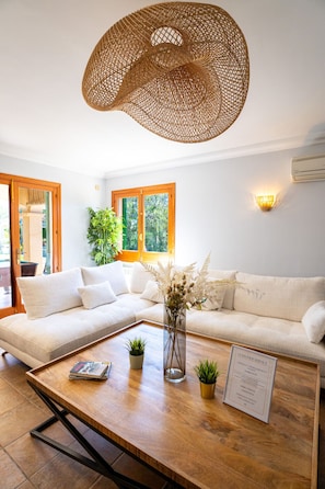 A modern living room with a sectional sofa, a coffee table with magazines, a decorative vase, and a customer service sign.
