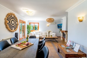 A dining area with a wooden table, chairs, and a fruit platter.