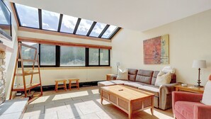 A spacious living room with a skylight, a sofa set, a coffee table, and a painting on the wall. - Large Center Village 1 Bedroom VS551 (Copper Mountain)