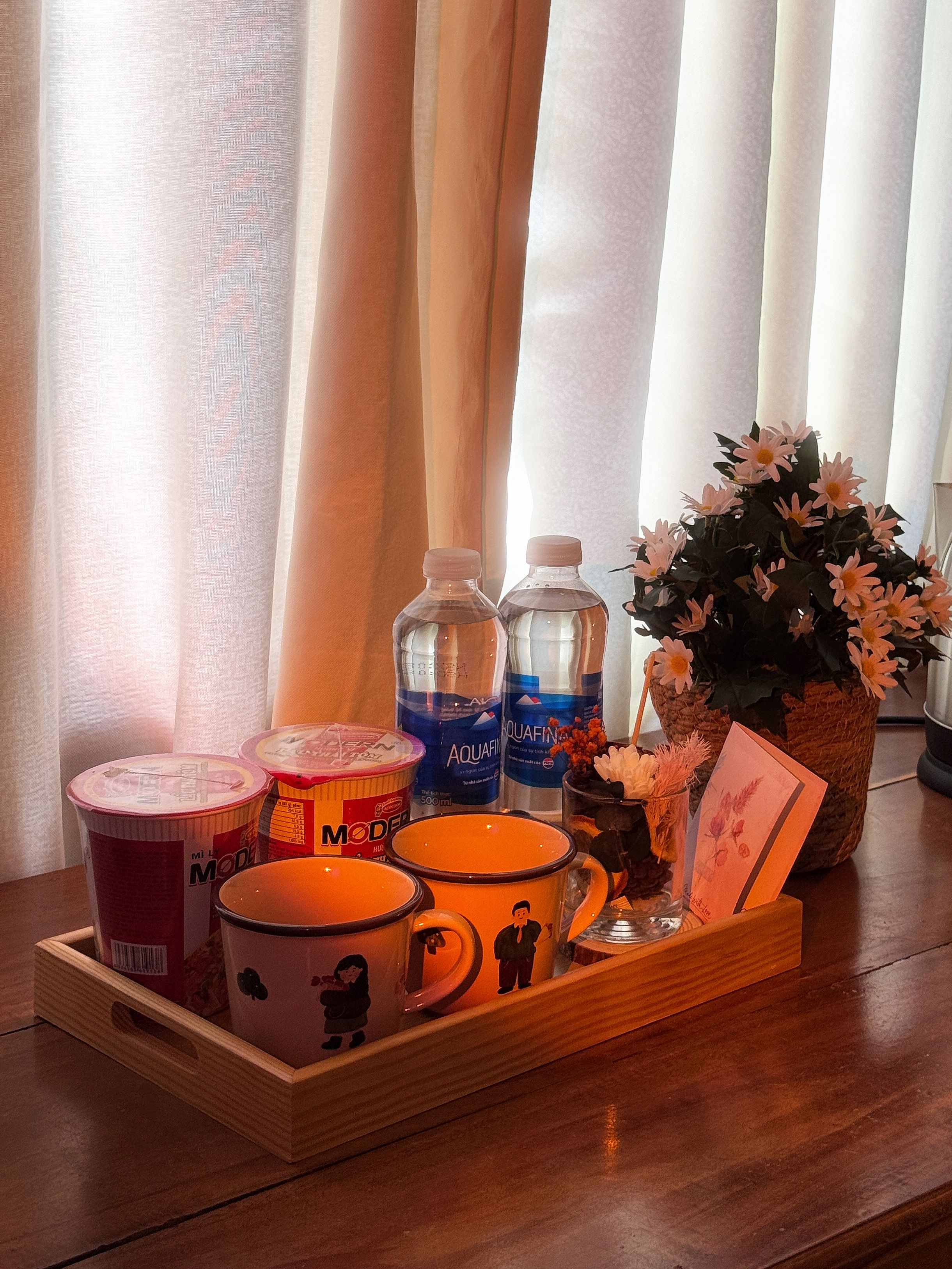 Uma bandeja com diversos itens, incluindo garrafas de água, uma caneca, um recipiente e um cartão.