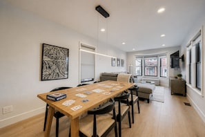 A dining area with a wooden table set for a game, a sofa, and a kitchen in the background. - Elevation 25 Your Pet Friendly Basecamp for Adventure (Park City)