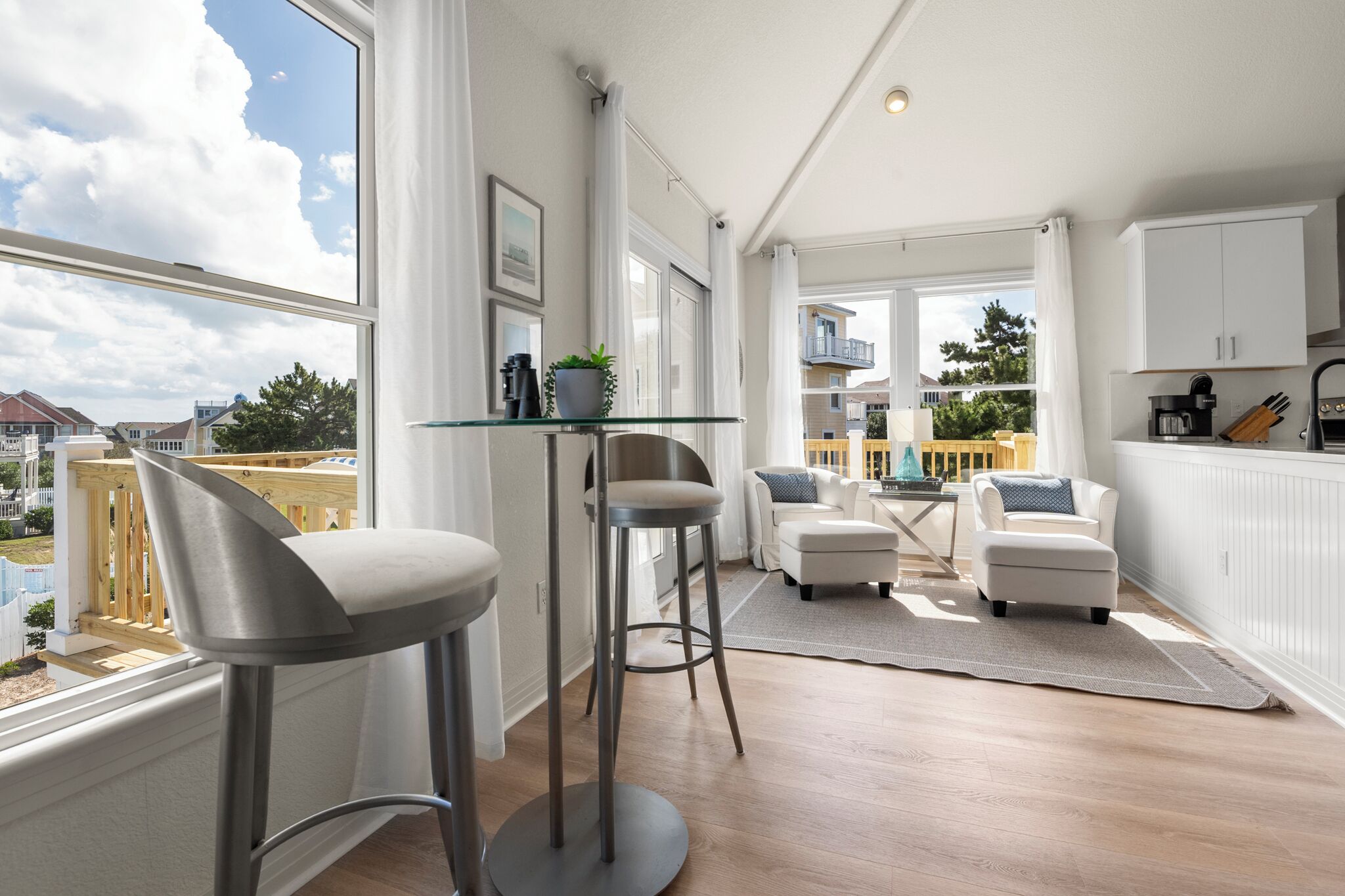 Une cuisine moderne avec une table à plateau en verre, des tabourets de bar et une vue sur le quartier.