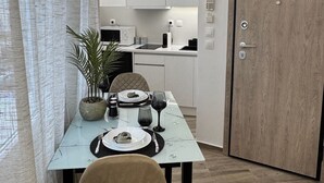 Ein moderner Essbereich mit Tisch für zwei Personen, einem Topf mit Pflanze und Blick in die Küche.