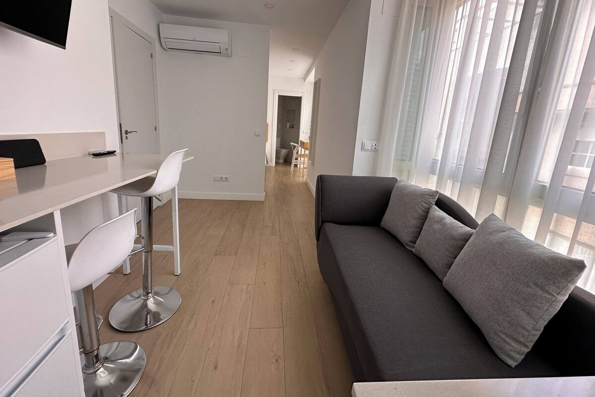A modern living room with a sofa, a dining area, and a kitchen.