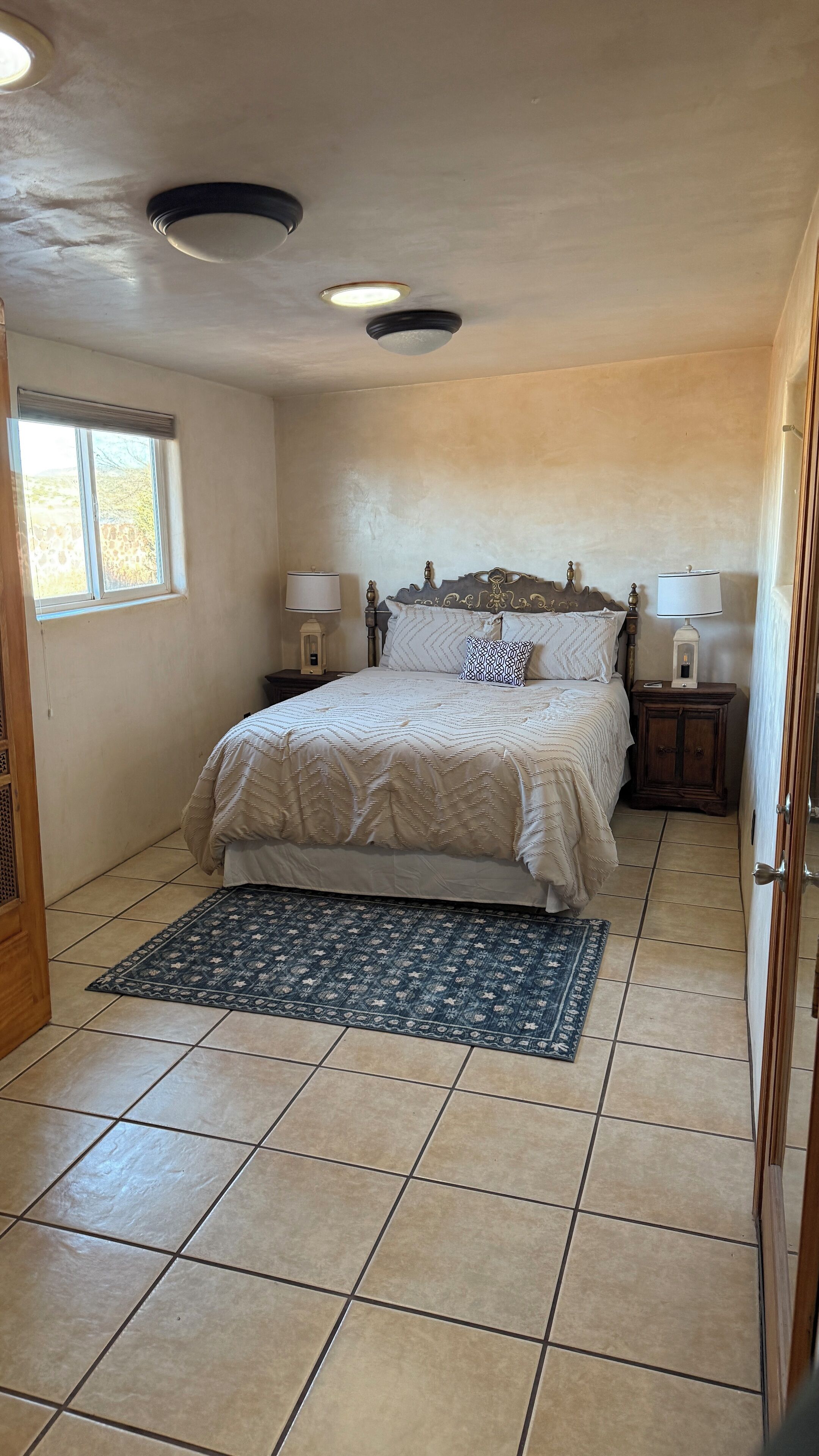 A bedroom with a bed, nightstands, a rug, and a window.