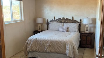 A bedroom with a bed, nightstands, a rug, and a window.