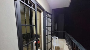 A corridor with a white plastic chair, a black metal gate, and a ceiling light.