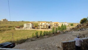 A stone pathway leading to a row of multi-story buildings with a clear view of the surrounding landscape.