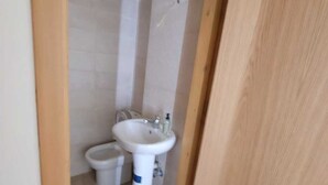 A small, narrow bathroom with a white sink and toilet.