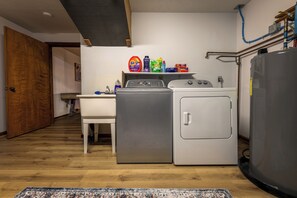 Un lavadero pequeño con lavadora, secadora y un calentador de agua grande.