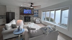 Una sala de estar moderna con chimenea de piedra, televisor de pantalla plana y un ventanal con vistas.