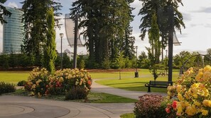 A park with a paved walkway, benches, and flower beds. - Central Surrey Gem – Steps from SkyTrain, Dining & Groceries (Surrey)