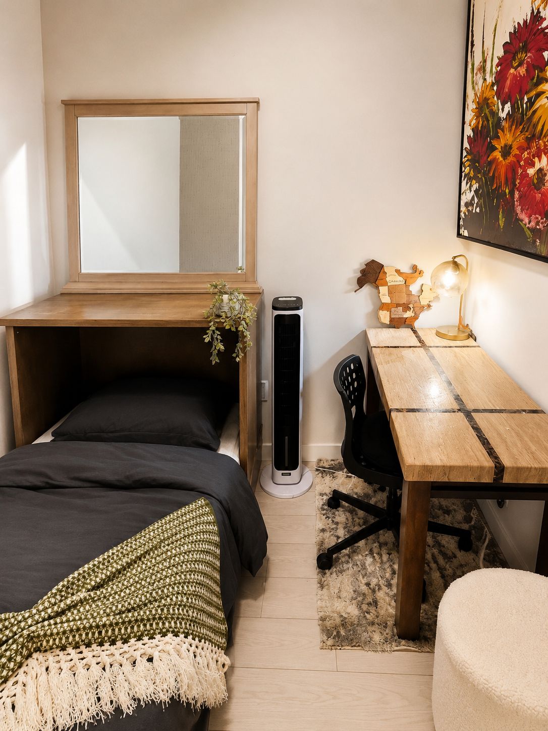 Une chambre à coucher de taille réduite, comprenant un lit, un bureau, une chaise, un miroir, un radiateur et un globe terrestre décoratif.