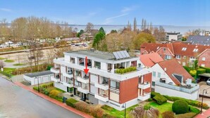 A modern multi-story residential building with a flat roof, solar panels, and a balcony. - 300m to the fine Baltic Sea beach - Comfort vacation apartment Seemöwe Scharbeutz (Scharbeutz)