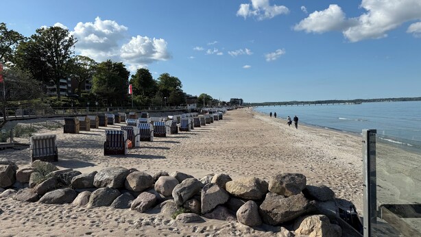 A beach with rows of beach chairs and umbrellas, a rocky shoreline, and a calm sea. - 300m to the fine Baltic Sea beach - Comfort vacation apartment Seemöwe Scharbeutz (Scharbeutz)