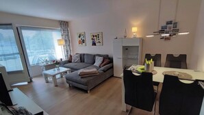 A modern living room with a sofa, coffee table, and dining area with chairs. - 300m to the fine Baltic Sea beach - Comfort vacation apartment Seemöwe Scharbeutz (Scharbeutz)