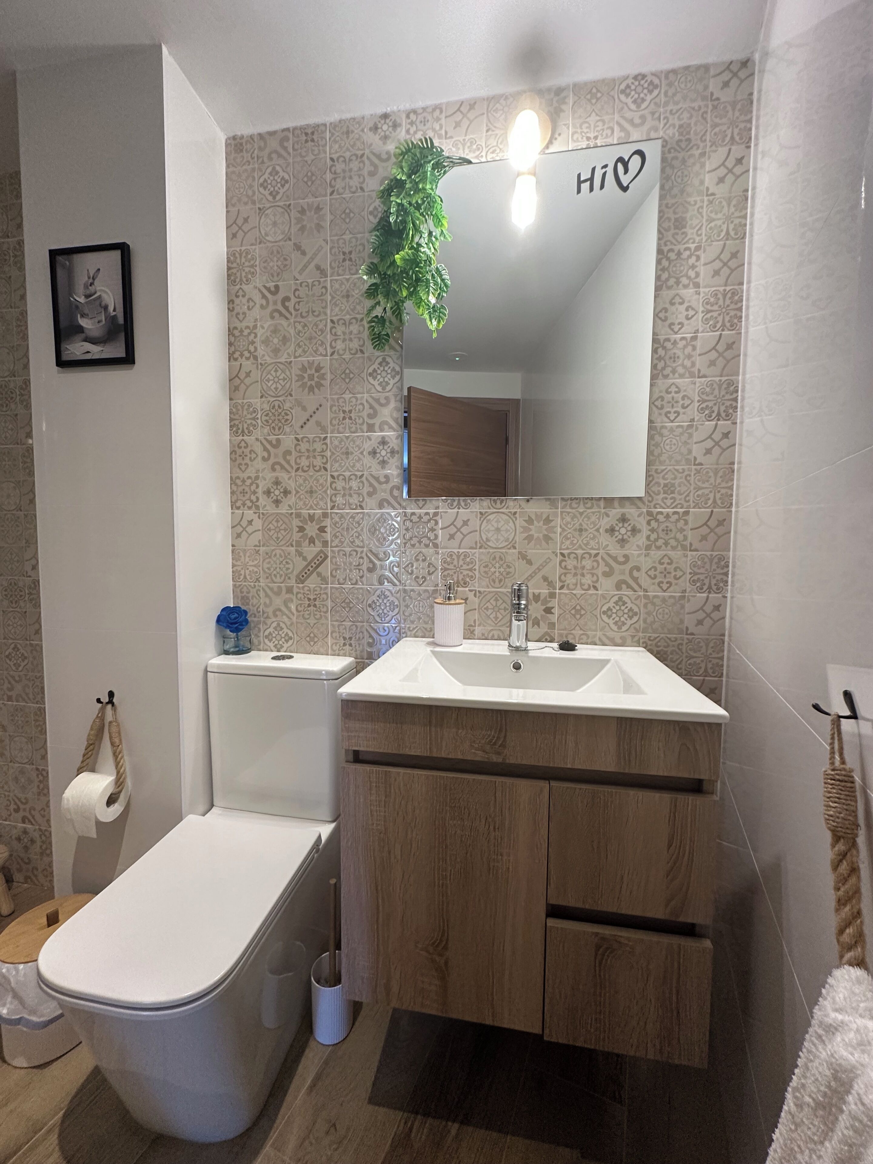 Un baño con inodoro, lavamanos y espejo.