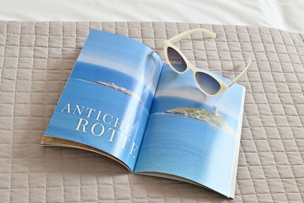 A book titled "ANTICHE ROTTE" on a quilted surface with a pair of sunglasses on top.