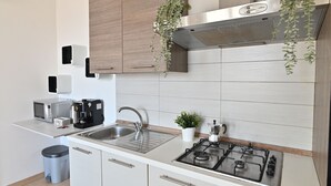 Een moderne keuken met een roestvrijstalen spoelbak, een gasfornuis, een magnetron en een koffiezetapparaat.