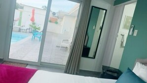 Una habitación de hotel con cama, ventana y vista al área de una piscina al aire libre.
