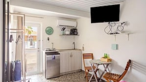 Une cuisine compacte équipée d’un évier, d’une cuisinière et d’un téléviseur à écran plat fixé au-dessus du plan de travail.