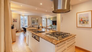 A modern kitchen with a central island, stainless steel range hood, and a dining area with a view.