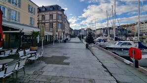 A marina with boats docked, a café with outdoor seating, and buildings with balconies.