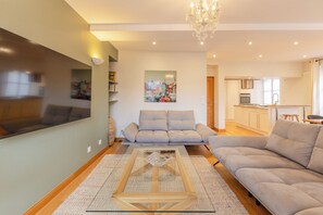 Een moderne woonkamer met een bank, een salontafel en een keuken op de achtergrond.