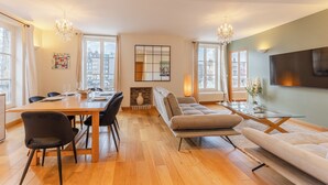 A modern living room with a dining area, large windows, and a fireplace.