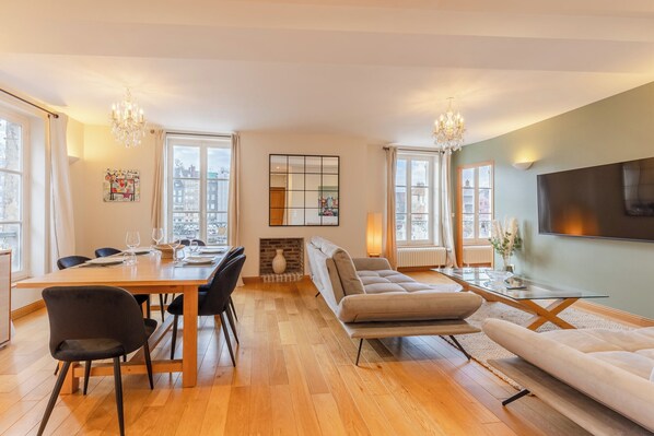 A modern living room with a dining area, large windows, and a fireplace.