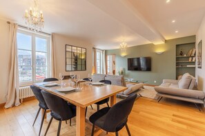 Een moderne woonkamer met een eethoek, een bank, een televisie en uitzicht over de stad.