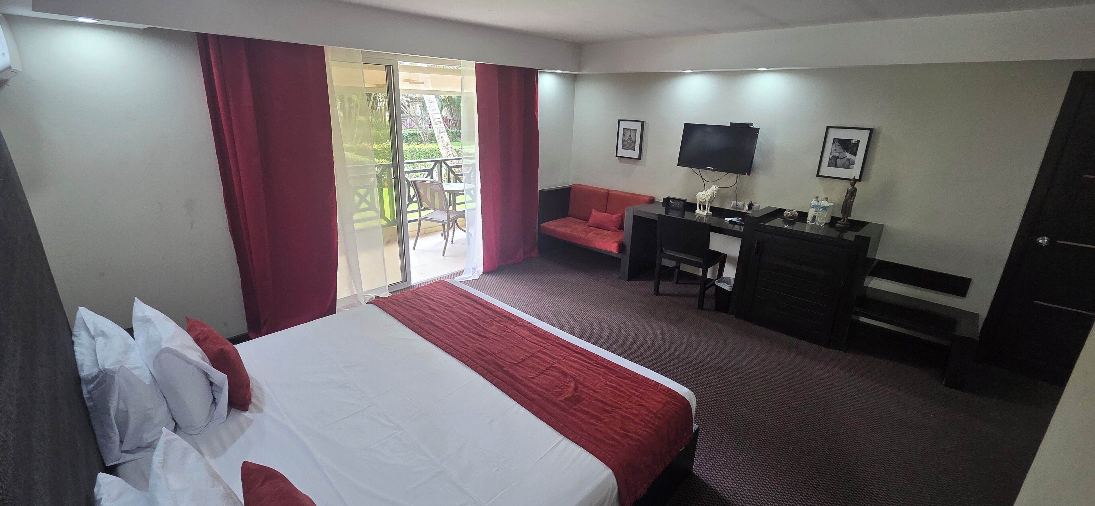 Ein Hotelzimmer mit Bett, Schreibtisch, Stuhl, Sofa und Fernseher.