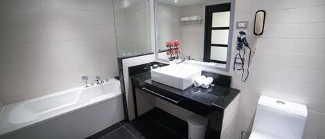 A modern bathroom with a bathtub, a sink with a mirror, and a toilet.