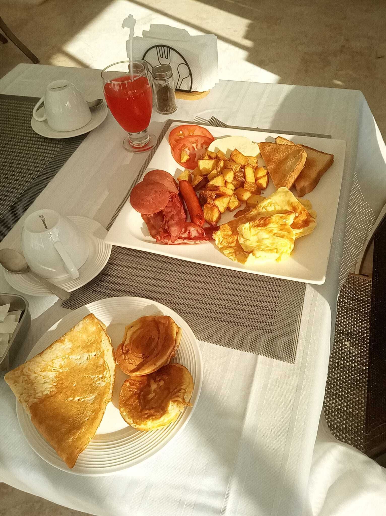 Ein Esstisch mit Eiern, Toast und Kartoffeln, einer Tasse Tee und einem Teekessel.