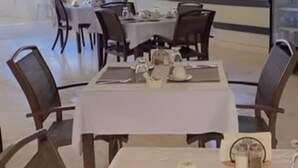 Un espace repas avec des tables disposées pour accueillir quatre personnes, des chaises et une vue sur la verdure environnante.