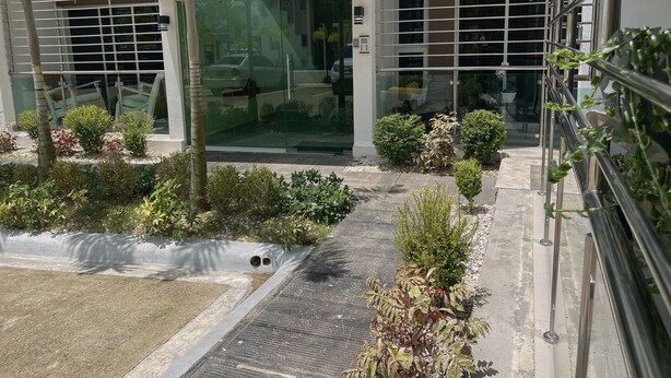 Een modern gebouw met glazen ingang, een verhard pad en aangelegde beplanting.