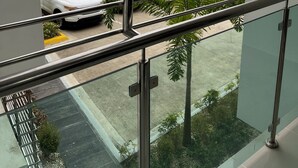 Uitzicht vanaf een balkon met metalen hekwerk, over een parkeerplaats met meerdere auto's en palmbomen.