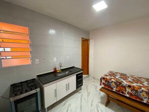 Geladeira, fogão, talheres/pratos/utensílios de cozinha, mesas de jantar