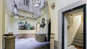 A narrow hallway with a stone fountain, potted plants, and a staircase leading to an upper level. - PIAZZA NAVONA ADORABLE APARTMENT (Roma)