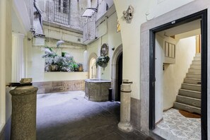 A narrow hallway with a stone fountain, potted plants, and a staircase leading to an upper level. - PIAZZA NAVONA ADORABLE APARTMENT (Roma)