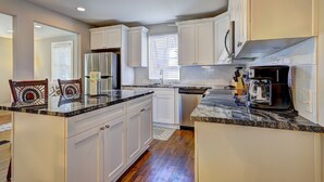 A modern kitchen with white cabinets, granite countertops, a stainless steel refrigerator, and a coffee maker. - Spacious 4-bedroom house in tranquil Decatur with AC (Decatur)