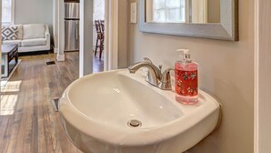 A bathroom with a white sink, a mirror, and a red soap dispenser. - Spacious 4-bedroom house in tranquil Decatur with AC (Decatur)