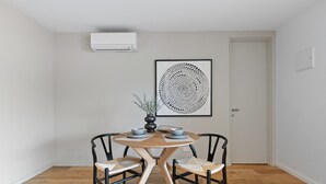 A dining area with a round wooden table, black chairs, and a woven rug. - Lovely 1-bed With Balcony in St Kilda's Heart (Melbourne)