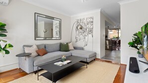 Una sala de estar moderna con un sofá gris, una mesa de centro negra y un cuadro abstracto grande en la pared.